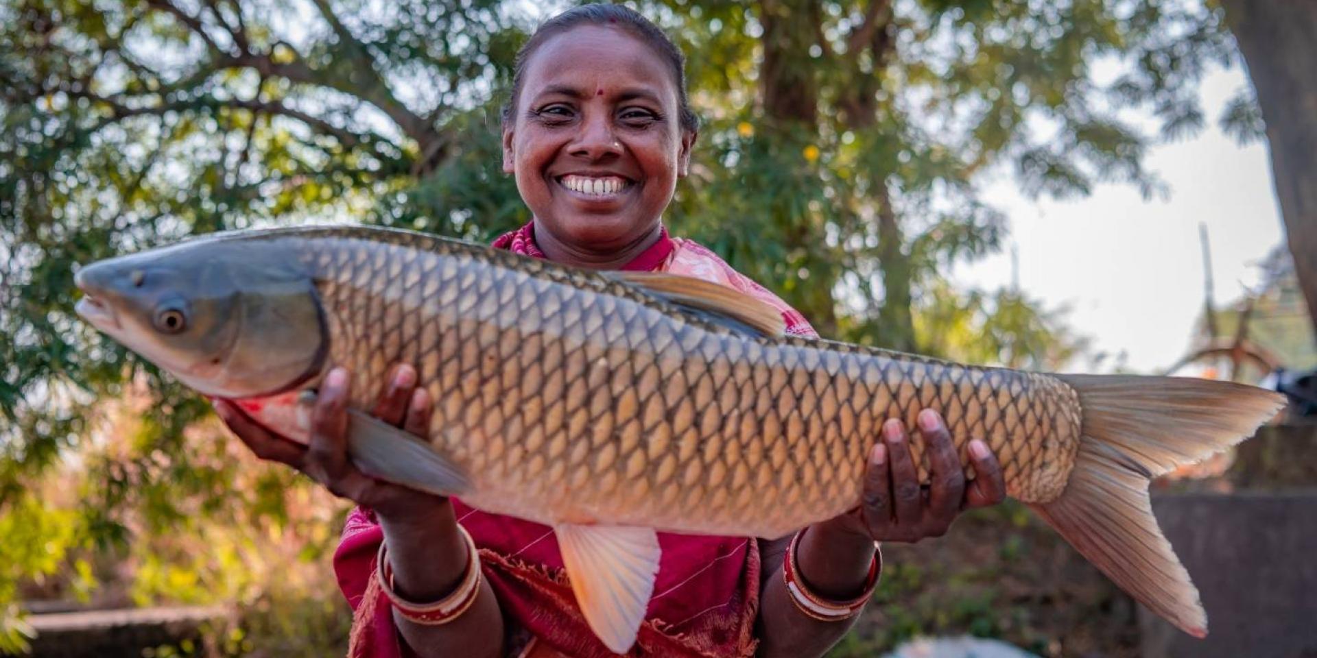 Indian woman smiling holding big fish