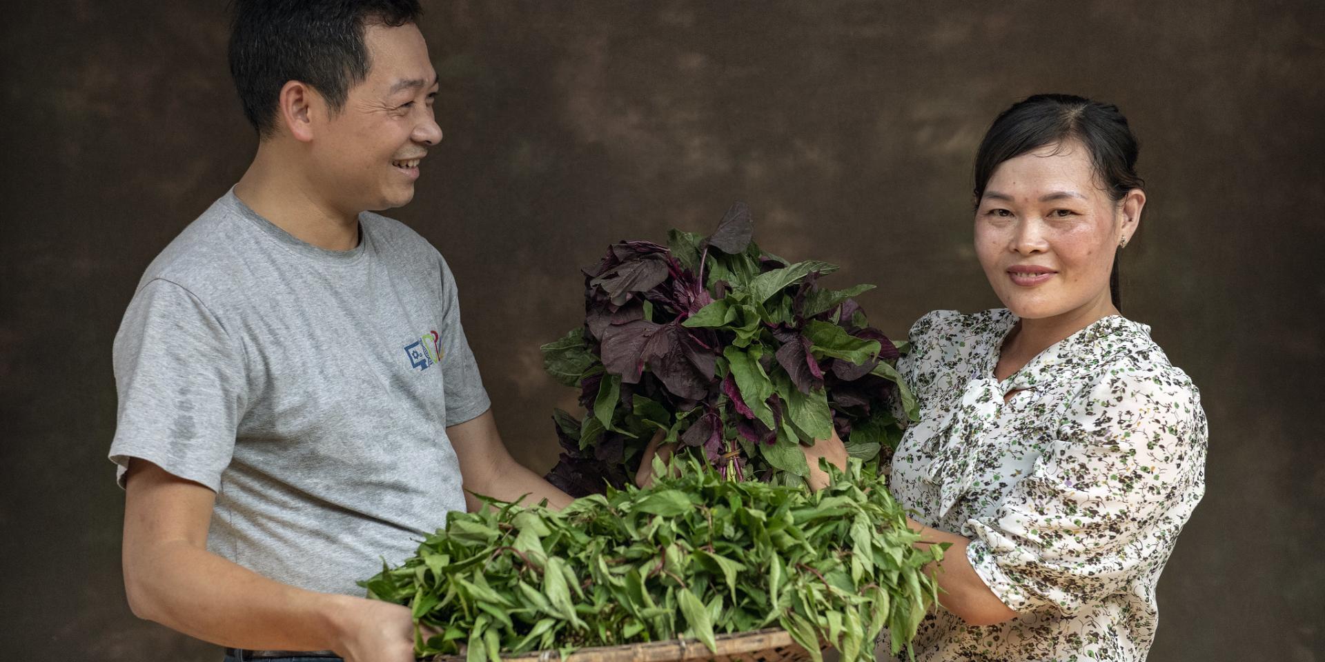 A man and a woman carrying vegetables