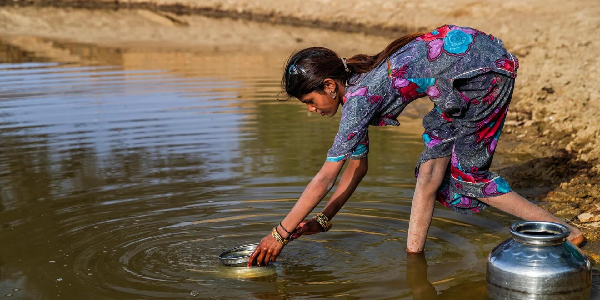 Woman gathering water from a river