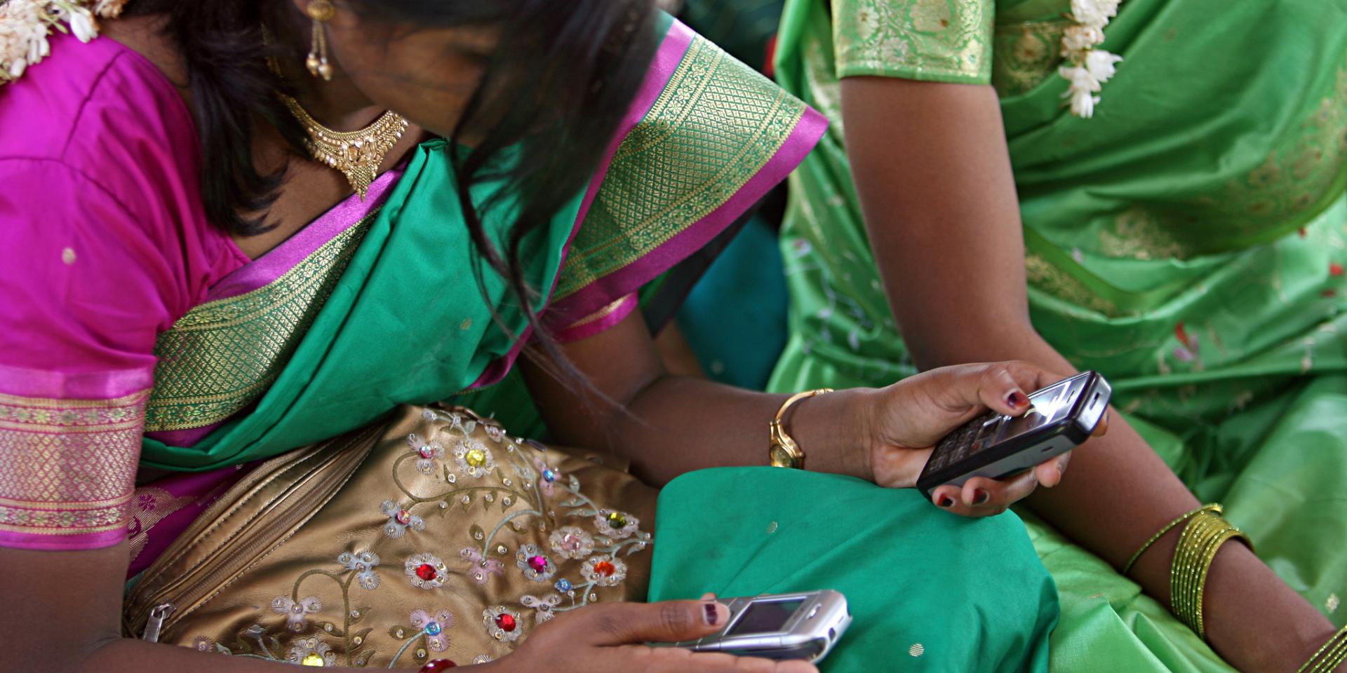 Two young Indian women look at two cellphones