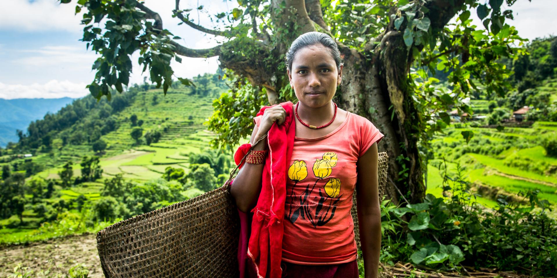 Young women standing with bamboo mat and rice paddy landscape behind her