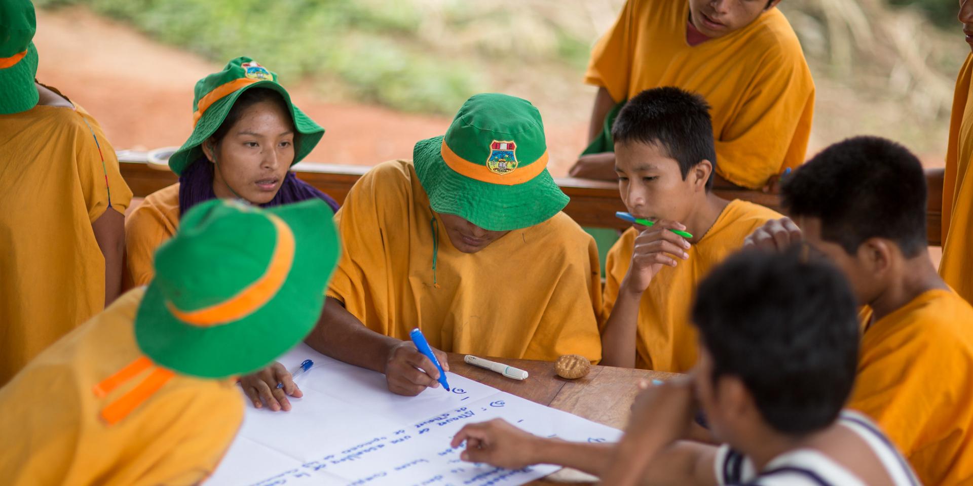 A group of young people seated around a table taking notes on a poster