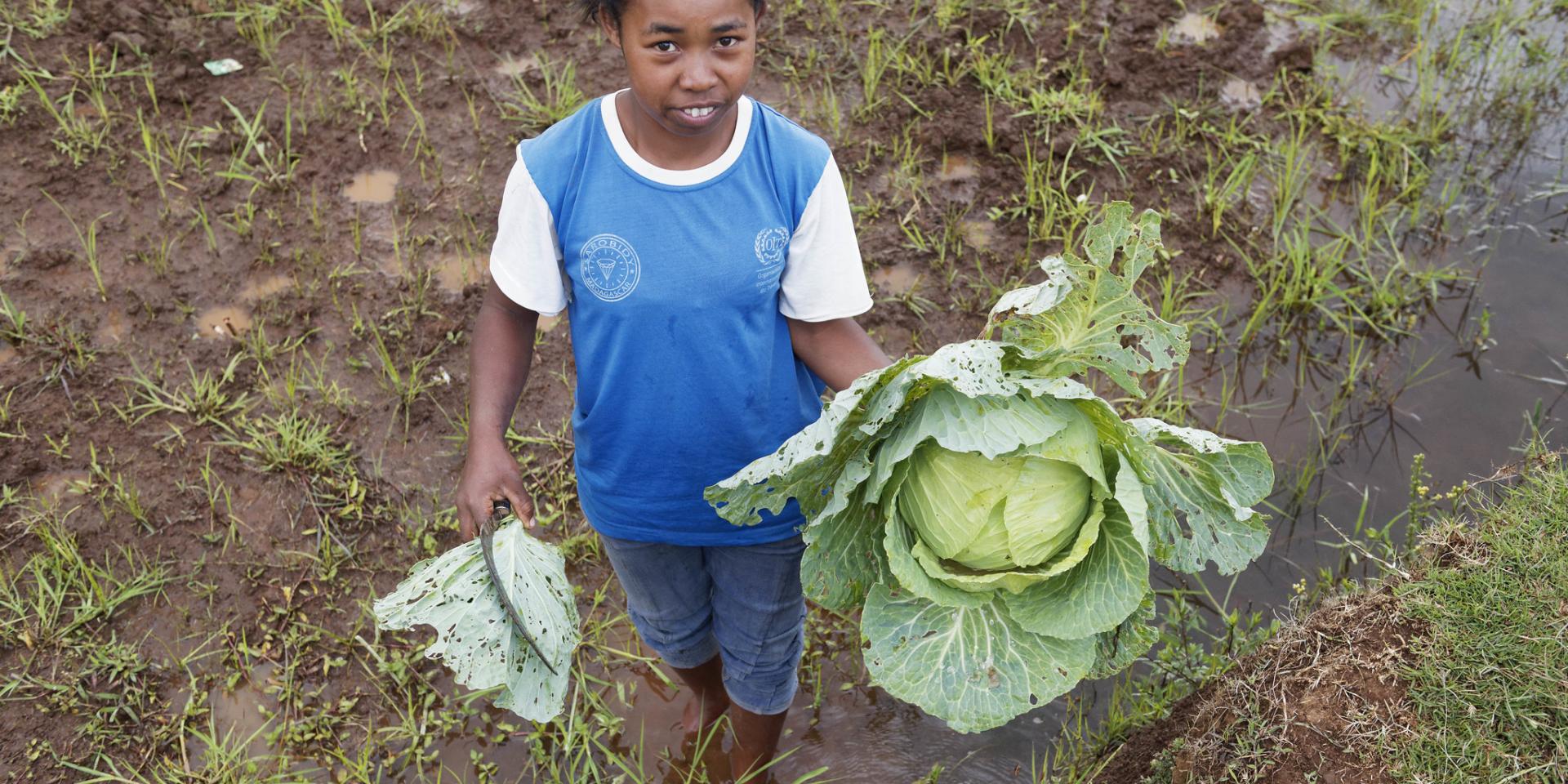 Photo of young women in field holding a big cabbage