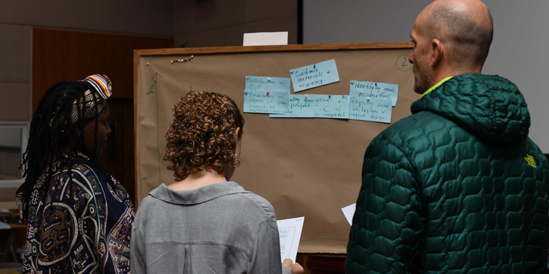 Researchers putting some sticky notes on a board