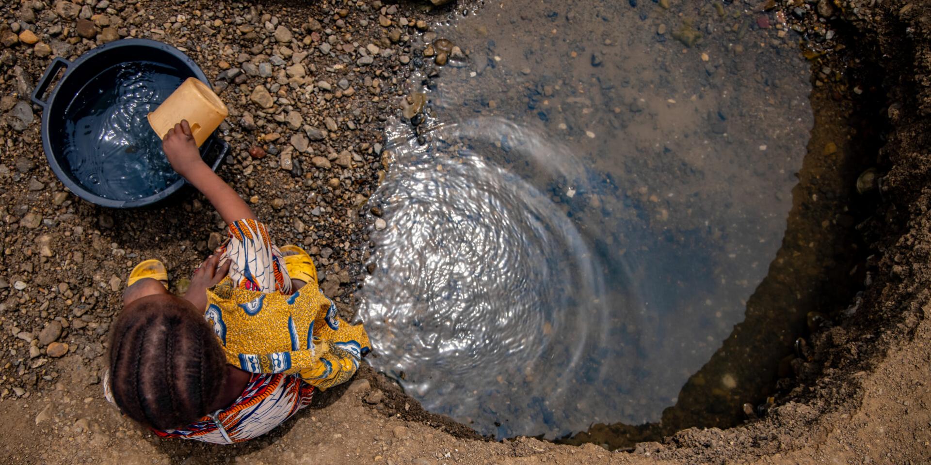 Girl fetching water from a dug out