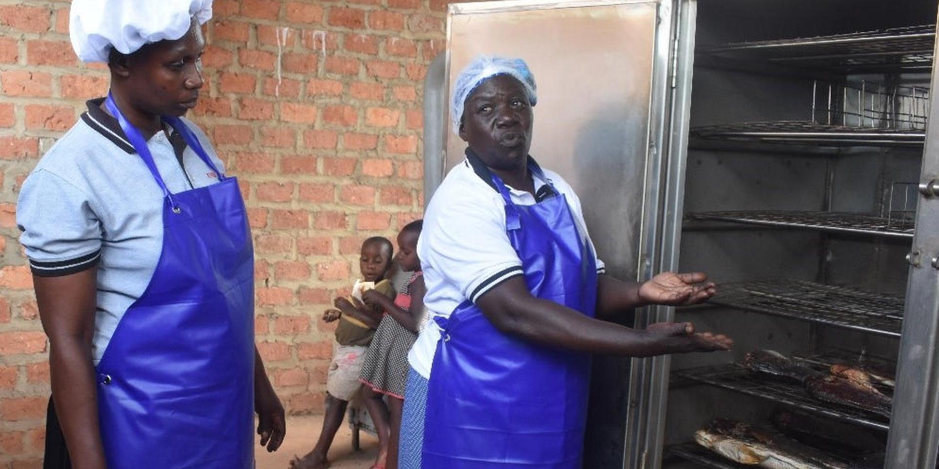 Princilla Nakato (right) shows how the new fish smoking kiln works at the Women of Hope Katosi Fish Processing Association. Copyright: Abraham Kibirige