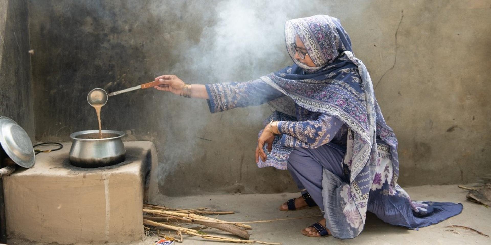 Woman cooking over firewood.