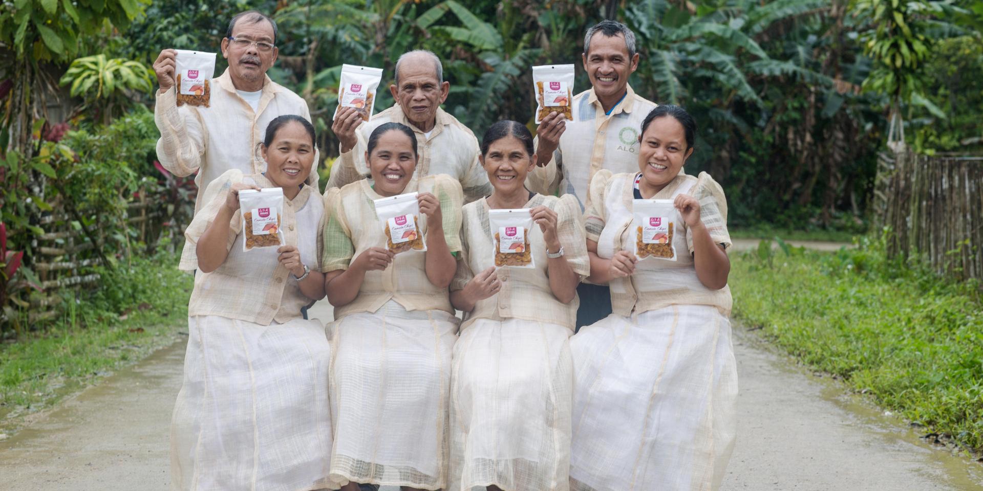 Women and men holding some sweetpotato products produced by their association