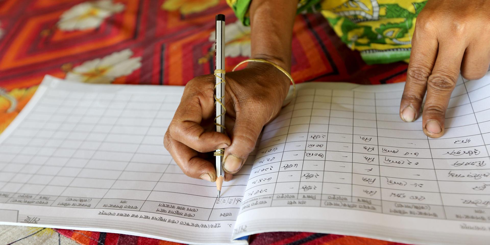 The woman writing data on her data entry book in Jessore, Bangladesh.