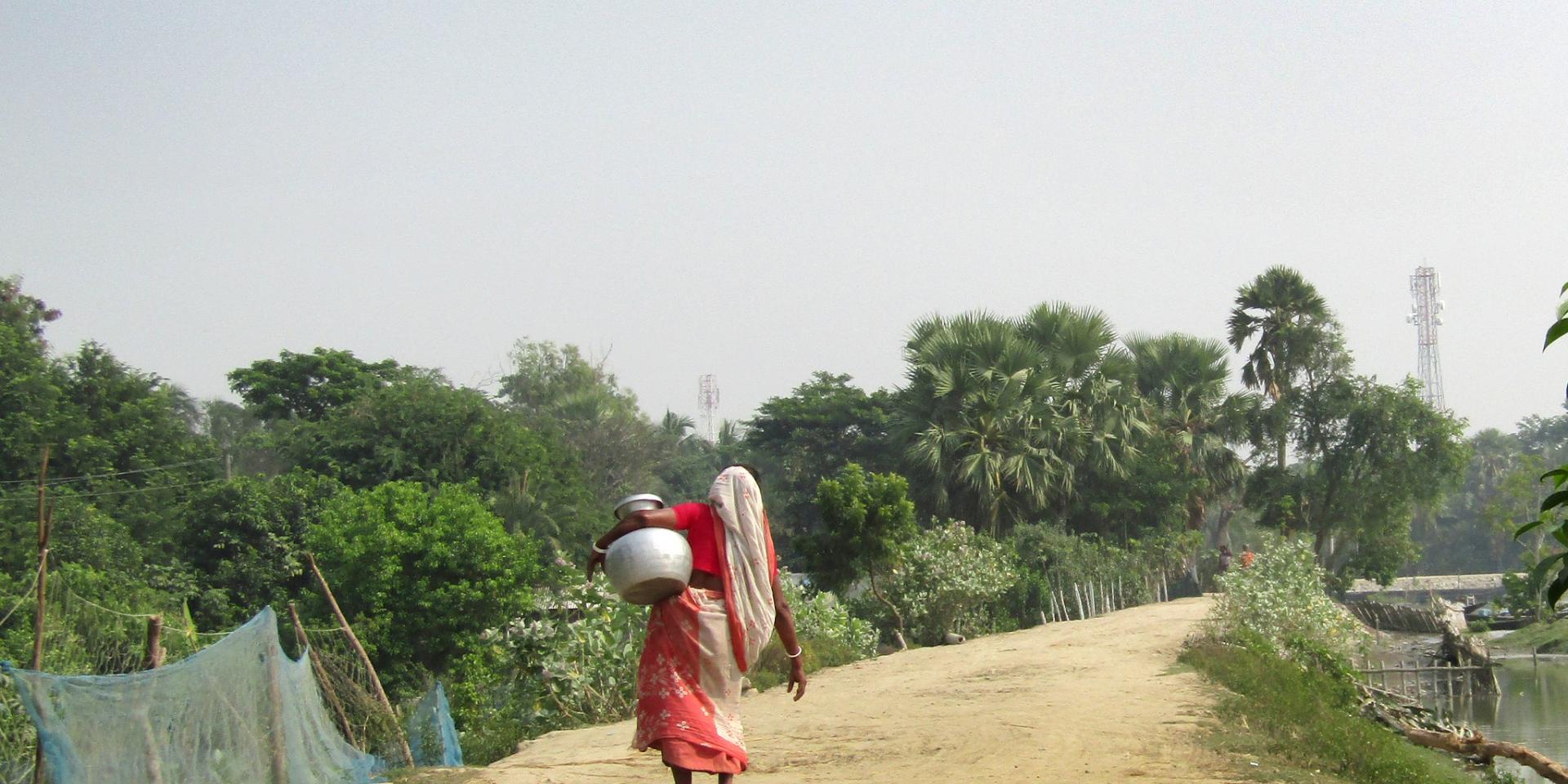 A woman carrying drinking water from a Pond Sand Filter (PSF) for her family in Bara Aria village of Polder 29.