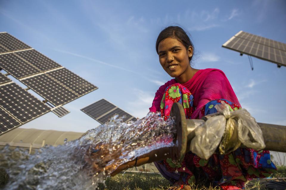 A farm worker uses the water pumped from a solar water pump in a farm.