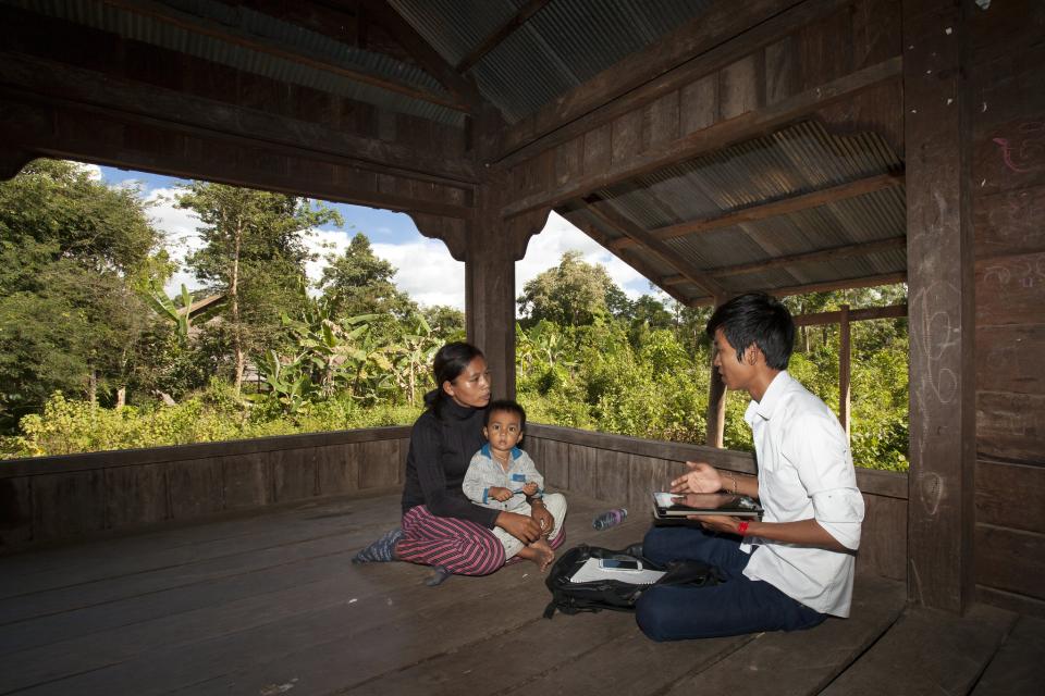 A researcher chatting with a woman farmer and her child