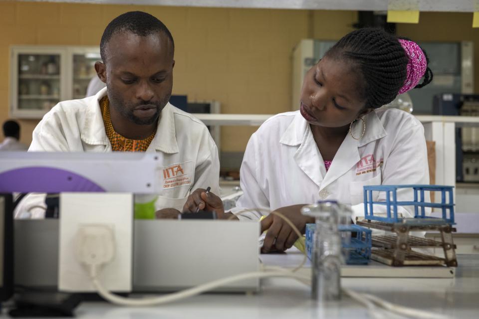 A woman and man sit at a desk in their lab coats, examining a sample