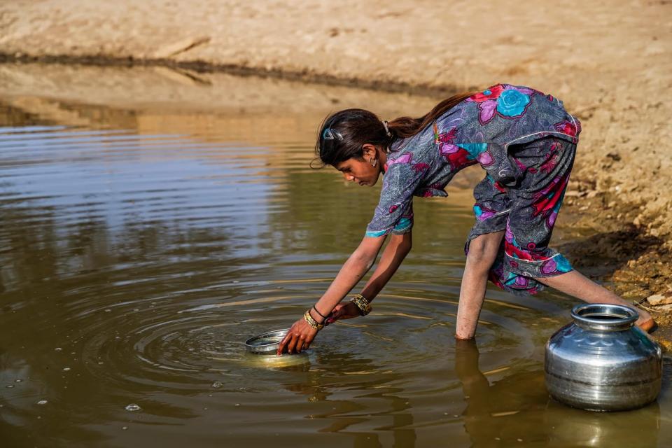 Woman gathering water from a river