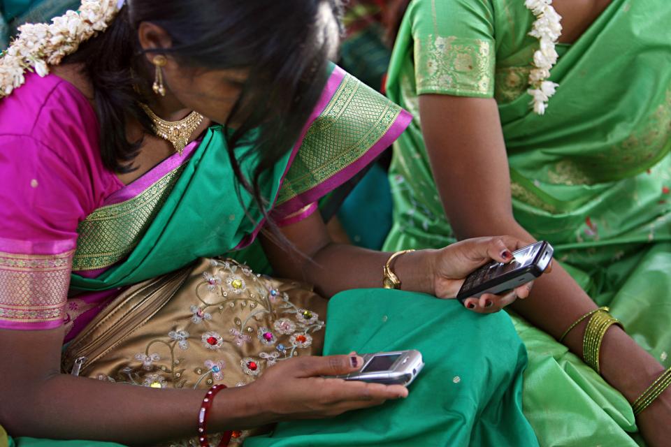 Two young Indian women look at two cellphones
