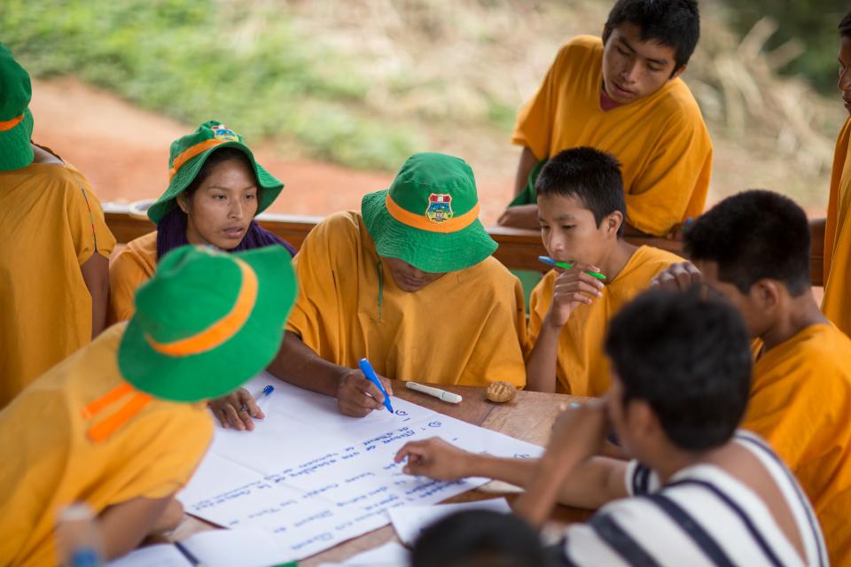 A group of young people seated around a table taking notes on a poster