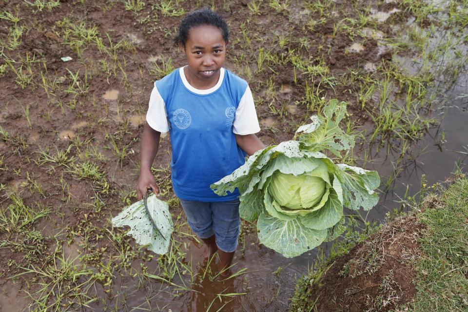 Photo of young women in field holding a big cabbage