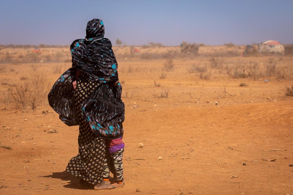 Drought in Ethiopia. A woman holding her child with dry landscape in the background