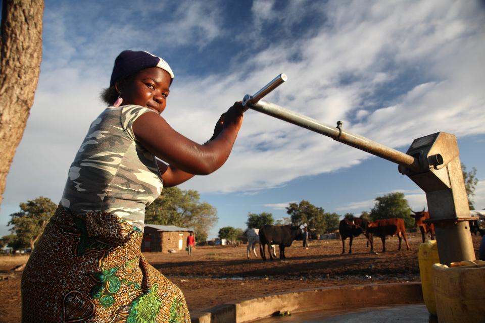 A woman pumps water for her livestock