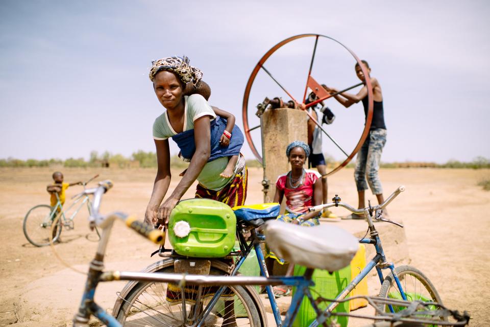 Barry Aliman, 24 years old, bicycles with her baby to fetch water for her family, Sorobouly village near Boromo, Burkina Faso. 