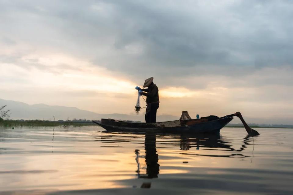 Photo of a fisherman fishing at sunset