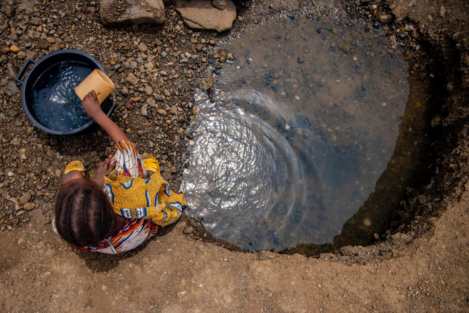 Girl fetching water from a dug out