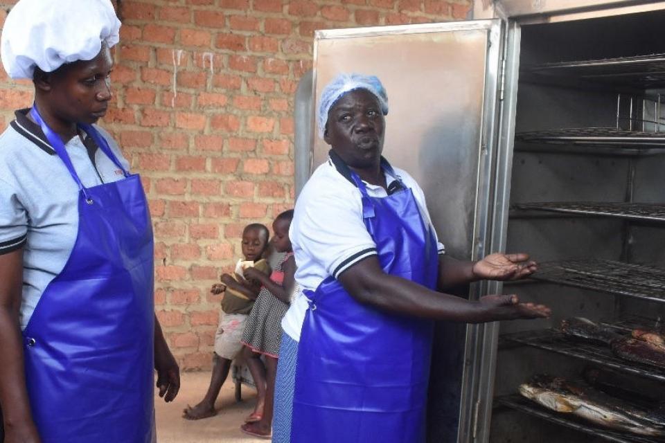 Princilla Nakato (right) shows how the new fish smoking kiln works at the Women of Hope Katosi Fish Processing Association. Copyright: Abraham Kibirige