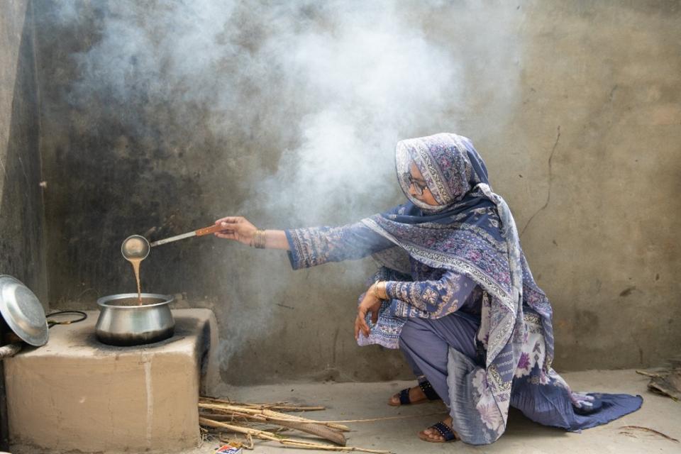 Woman cooking over firewood.