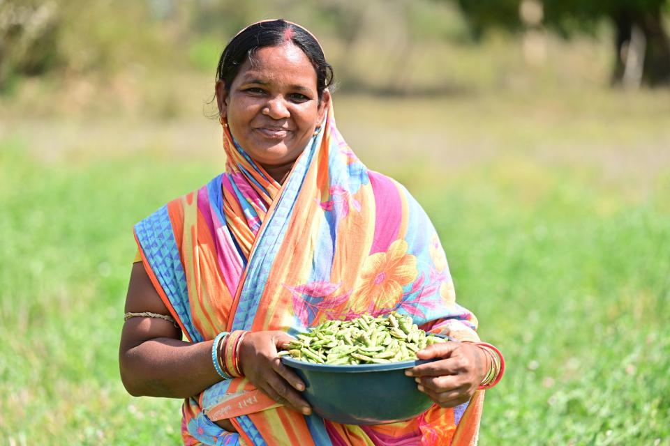 Woman holding a tin small basin of peas