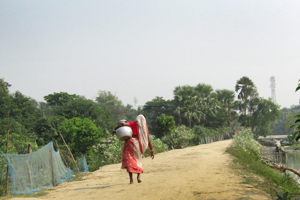 A woman carrying drinking water from a Pond Sand Filter (PSF) for her family in Bara Aria village of Polder 29.
